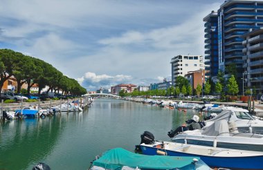 Grado, Friuli Venezia Giulia / İtalya - 15 Mayıs 2023: Grado, İtalya. Suda motorlu tekneler, arka planda modern binalar olan bir kanal manzarası..