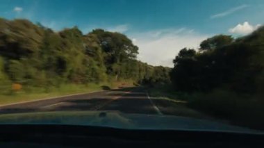 Arabanın ön camında yüksek hızda yol var. Arabanın plakası asfalt yolda ilerliyor.