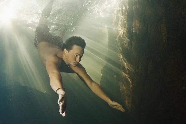 人类在淡水河中潜水 阳光闪烁着穿过水面 在岩石边游动 — 图库照片
