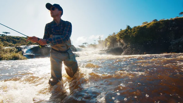 フライフィッシング ウェーダーの漁師は急速な濁った川のラインをキャストします — ストック写真
