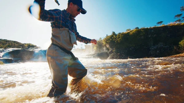 急速な川で釣りをフライ 漁師はゆっくりと激怒した濁った川から歩く — ストック写真