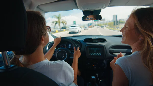 2人の若い女性が車で旅行する 陽気な女性は 高速道路を走行しながら 現代の車の中で音楽やダンスを聴く座っている — ストック写真