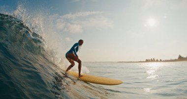 Sıska kadın sörfçü dalgada sörf yapıyor. Kadın, Maldivler 'deki okyanus dalgalarında sörf yapar. Sarı bir sörf tahtası üzerinde.