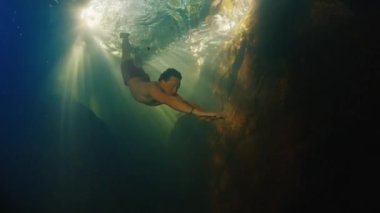 İnsanlar tatlı su nehrine dalarlar. Güneş ışınları suyun içinde parlar.