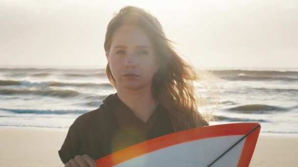 傲慢的冲浪手年轻的女人站在海滩上与冲浪板并看着相机 — 图库视频影像