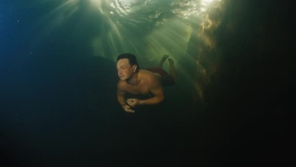 Mann Taucht Süßwasserfluss Mit Sonnenstrahlen Durch Das Wasser — Stockvideo