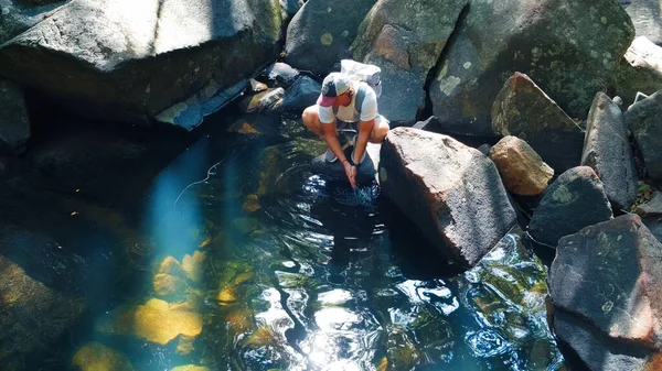 男ハイカーはきれいな森の川で手を洗う — ストック写真
