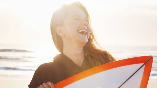 女冲浪者站在热带海滩上和冲浪板一起笑着 — 图库照片