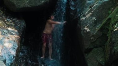 Genç adam duş alır ve şelalede kendini tazeler.