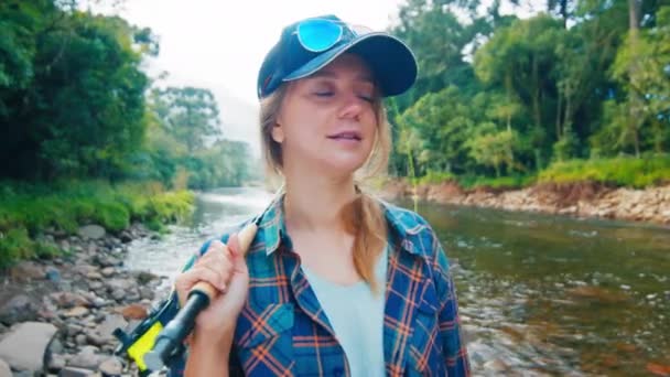 農村部の漁業者 川の近くに釣り竿を持って立って釣り服を身に着けているきれいな女性釣り人の肖像画 — ストック動画