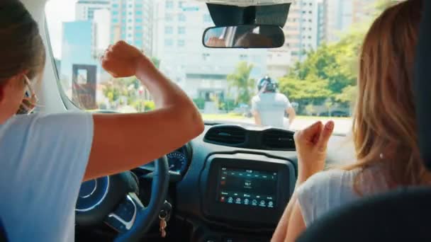 女士在车上 两个年轻女子在城市里开车 边跳舞边等红绿灯 — 图库视频影像