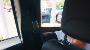 Otoparkın parasını arabadaki kadın ödüyor. İki genç kadın bir şehirde araba sürüp otoparka giriyor.