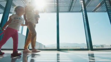 Ailesi havaalanında. İki çocuklu bir anne havaalanında bavulla yürüyor. Kız ailesiyle yürür ve kendi bavulunu taşır.