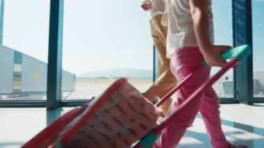 Ailesi havaalanında. İki çocuklu bir anne havaalanında bavulla yürüyor. Kız ailesiyle yürür ve kendi bavulunu taşır.