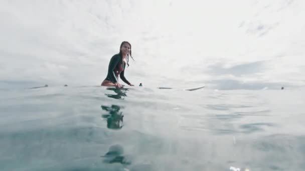 Female Surfer Sits Surf Board Ocean Looks Camera Laughs — Stock Video