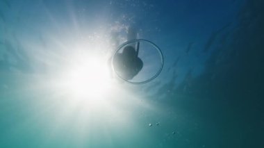 Serbest dalgıç bulanık denizde su altında yüzer ve halka baloncuğunun içinde süzülür. Freediver halka baloncuğu ile su altında oynar