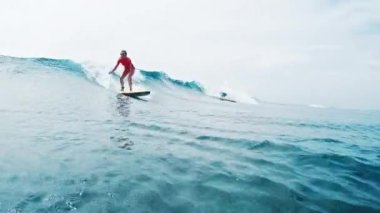 Kadın sörfçü dalgada sörf yapıyor. Aşırı yavaş çekimde warp efekti