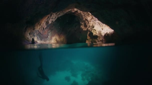 フリーダイバーは洞窟の水中を泳いでいる 男性の解放された肝臓は洞窟を探検し その中に水中で泳ぎます — ストック動画