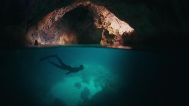 フリーダイバーは洞窟の水中を泳いでいる 男性の解放された肝臓は洞窟を探検し その中に水中で泳ぎます — ストック動画