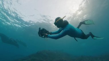 Sualtı fotoğrafçısı Manta Ray 'in fotoğrafını çeker. Resifin üzerinde yüzen dev okyanus Manta Ray 'i kameralı Freediver. Nusa Penida, Bali, Endonezya