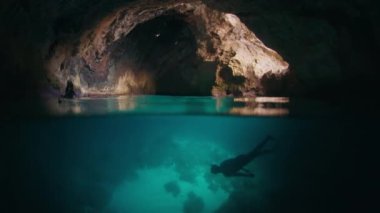 Freediver mağarada suyun altında yüzer. Erkek serbest dalgıç mağarayı keşfeder ve içinde yüzer.