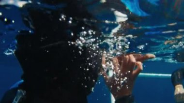 Freediver saatlerini platformun derinliklerinden açık denizde sürüklenmeden önce ayarlar.