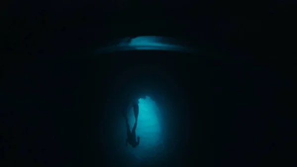 フリーダイバーは洞窟の水中を泳いでいる 男性の解放された肝臓は洞窟を探検し その中に水中で泳ぎます — ストック写真