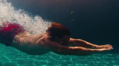 Havuzda köpüklerle süzülen adamın sineması. Adam havuza atlıyor ve su altında süzülüyor, kusursuz bir döngü görüntüsü.