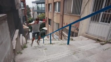 Adam şehir merkezinde spor yapıyor. Genç ve formda bir adam şehirde merdivenlerde egzersiz yapıyor.