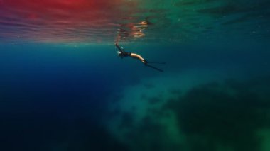 Freediver 'ın sineması ve yansıması. Serbest dalış yapan kadın denizde yüzer ve yüzeye yavaşça yüzeye çıkar.