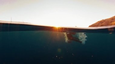 Kadın serbest dalgıç derinlerden yükselir, yüzeyde belirir ve nefes almaya başlar.