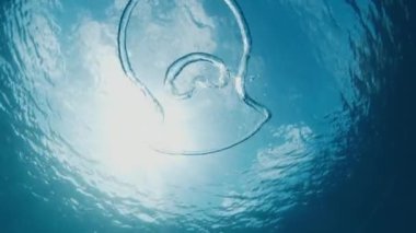 Halka baloncukları suyun altında hareket eder, çarpışır ve yeni küçük kabarcıklar oluşturur.