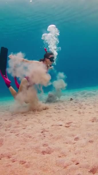 ピンクのスーツで解放された女性は 水中の泡を吹き飛ばし 熱帯の海で泳ぐことを楽しむ — ストック動画