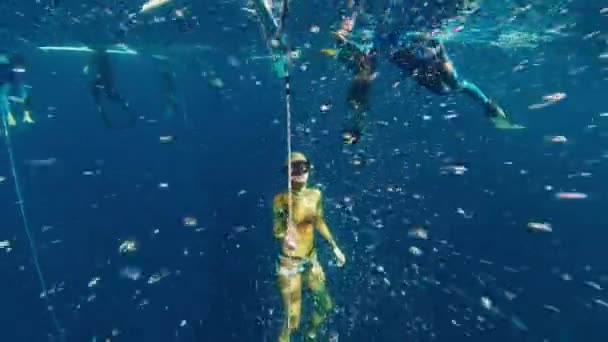 在海里用绳子挣脱 女自由者慢慢地沿着绳子向上攀爬 照相机在微小的气泡云中穿行 — 图库视频影像