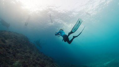 Sualtı fotoğrafçısı Manta Ray 'in fotoğraflarını çekiyor. Resifin üzerinde yüzen dev okyanus Manta Ray 'i kameralı Freediver. Nusa Penida, Bali, Endonezya