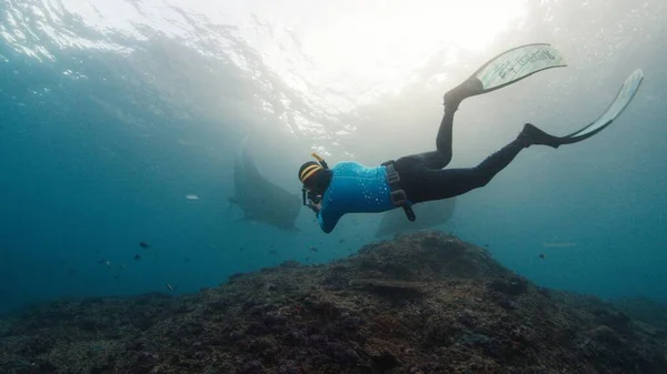 水中写真家はマンタ レイの写真を撮っている カメラフィルム付きフリーダイバー 巨大な海マンタレイ サンゴの上を泳いでいます Nusa Penida インドネシア ストック写真