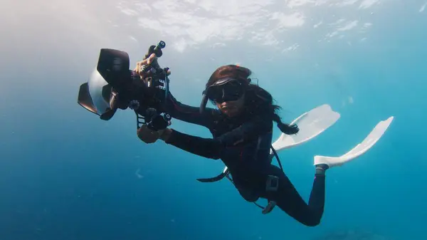 インドの水中写真家は 大きな水中カメラで泳いでいます 海で泳ぐカメラ付き女性フリーダイバー ストックフォト
