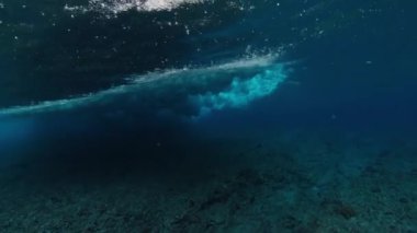 Resifin üzerinden okyanus dalgasının sualtı görüntüsü geçiyor.