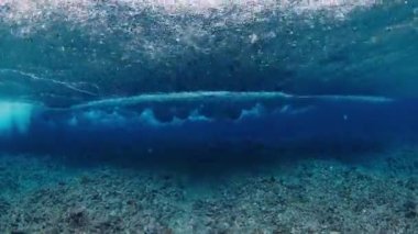 Resifin üzerinden okyanus dalgasının sualtı görüntüsü geçiyor.