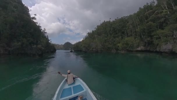 人站在移动的船的船头上 向司机发出航行指令 船在印度尼西亚Raja Ampat地区狭窄的航道上行驶 — 图库视频影像