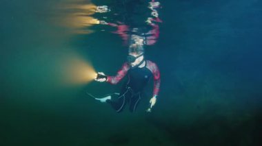 Freediver meşaleyle mağarada yüzer.