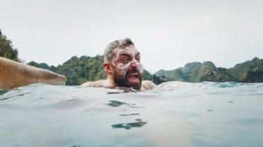 Papua kabilesinin yüz resmine kızgın adam suda yüzüyor ve öfkeyle bağırıyor.