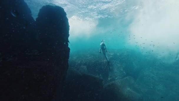フリーダイバーは海の下で泳ぎ 岩の近くに上昇する — ストック動画
