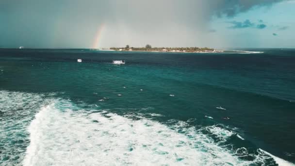今後の雨の中 サーファーが地平線に虹で波に乗ってサーフィンするスポットです モルディブ — ストック動画