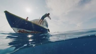 Sörfçü tekneden Maldivler 'deki temiz suya atlar.