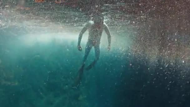 フリーダイバーは岩の近くの海で水中を泳ぐ — ストック動画