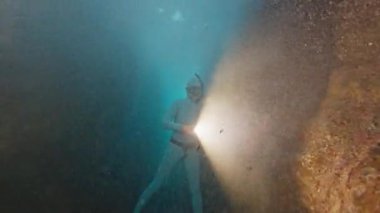 Freediver denizde suyun altında yüzer. İnsan kurtarıcı sualtı kanyonunda süzülür ve onu meşaleyle keşfeder.