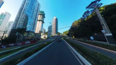 BALNEARIO CAMBORIU, BRAZIL - Mart 01, 2024: Kamera modern Brezilya şehrinde yüksek binalı yol boyunca hareket eder