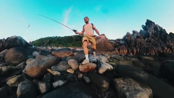 Günlük Kıyafetli Balıkçı Elinde Oltayla Kayalık Deniz Kıyısında Yürüyor — Stok video