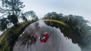 Balıkçı elinde oltayla nehrin ortasında duruyor.